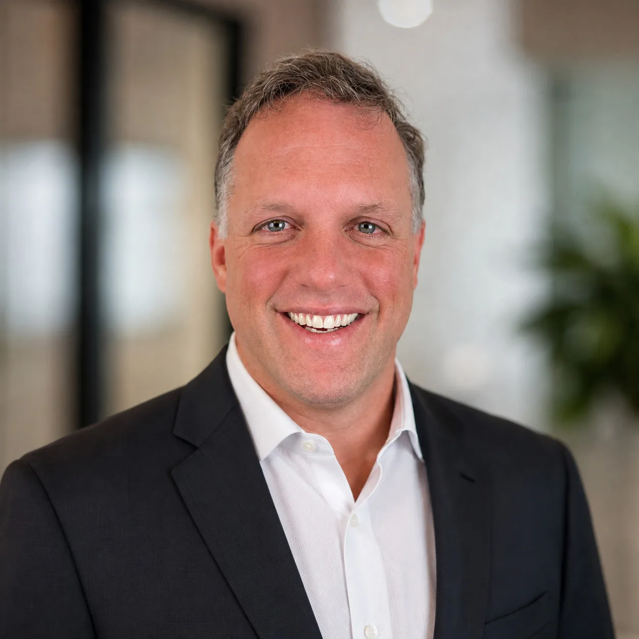 White man in business suit and shirt smiling